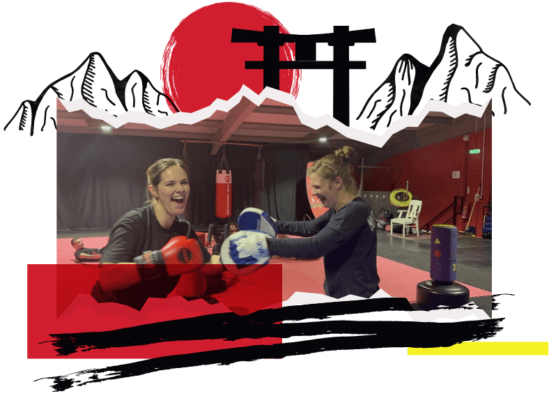 Two women practicing and laughing with boxing gloves and pads