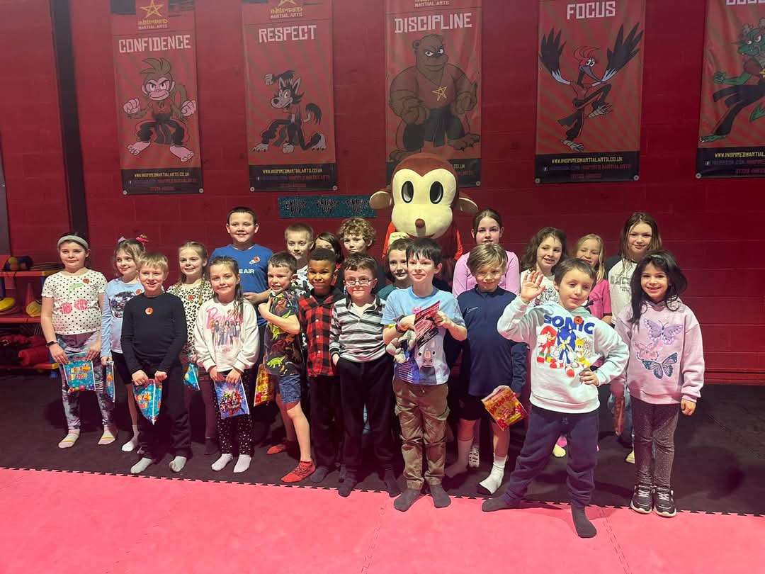 A birthday party with a group of children surrounding a monkey mascot