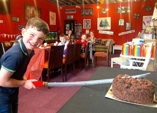 A child cutting a cake with a Katana sword